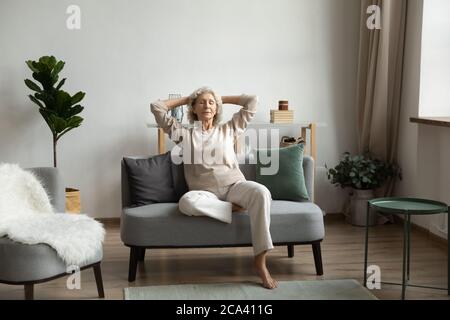 In living room on modern comfy couch relaxing mature woman Stock Photo