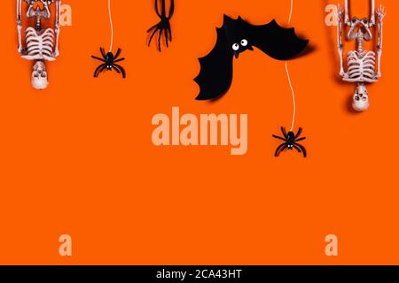 Halloween decoration concept - orange background with spiders, bat, skeletons. Flat lay, top view. A place for your text. Stock Photo