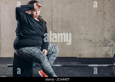 overweight woman looks tired after workout. close up photo. copy space. hobby, exhaustion, tiredness Stock Photo
