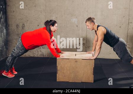sporty man and plump woman leaning on the box and working out. side view shot Stock Photo