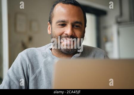 Close up smiling businessman happily working on laptop during coffee break in city cafe Stock Photo