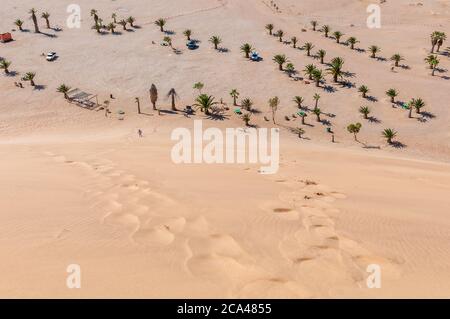 The view from Dune 7 at Walvis Bay on the Atlantic Ocean coast of Namibia. Palm trees and vehicles are visible Stock Photo