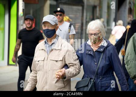 Elderly couple walking together, holding hands, wearing masks during COVID 19 post lockdown. Stock Photo