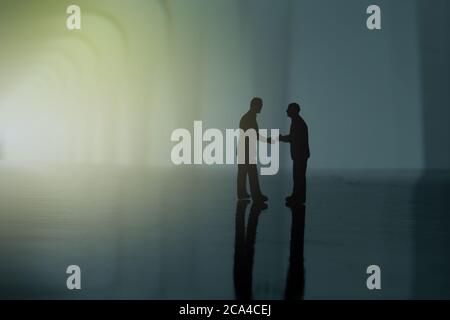 Silhouette of two businessmen make an handshake partnership agreement. Miniature people figure conceptual photography Stock Photo