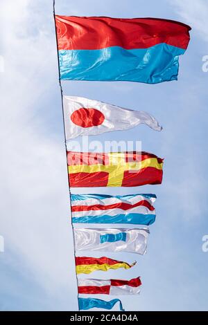 Nautical flags against blue sky in the wind at sunny day, vertical. Stock Photo