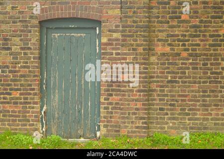 Ancient green wooden door on a brick wall forming a vintage background image Stock Photo