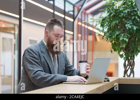 Bearded brutal caucasian hipster with paper sheet and cups Stock Photo ...