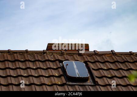 Brick chimney on an old house roof, blue sky, old roof window Stock Photo