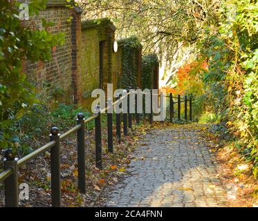 paved pathway with metal rail and brick wall on one side Stock Photo
