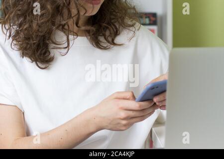 Young woman using phone in front of computer. Buying online concept. Copy space. Office interior Stock Photo