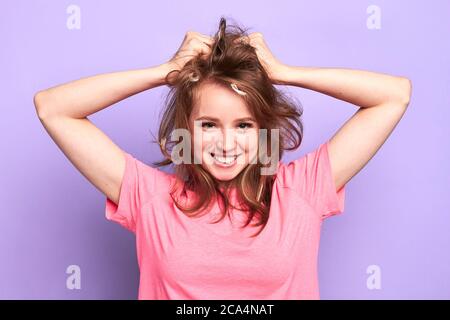 Photo of cheerful pretty girl smiling playfully, flirting with boy she likes at pyjamas pary, messing up her hair with hands after pillow fight, looki Stock Photo