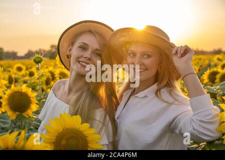 Portrait of young, happy blonde hair girls, sisters in a sunflower field. Stock Photo