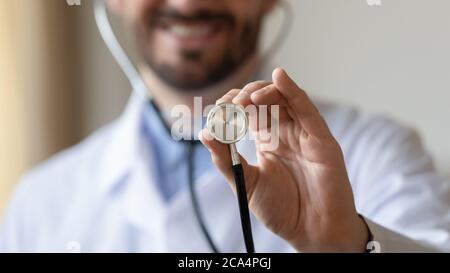 Close up focus smiling young male cardiologist holding stethoscope. Stock Photo