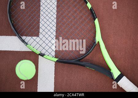 Tennis racket and ball on red-clay tennis court background Stock Photo