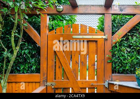 Wooden gate and fence on the back of the home garden. The gate is closed with a padlock. Stock Photo