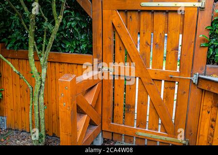 Wooden gate and fence on the back of the home garden. The gate is closed with a padlock. Stock Photo