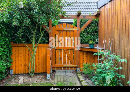 Wooden gate and fence on the back of the home garden. The gate is closed with a padlock. Stock Photo