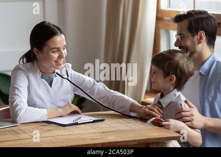 Friendly young pediatrician listening lungs of small patient. Stock Photo