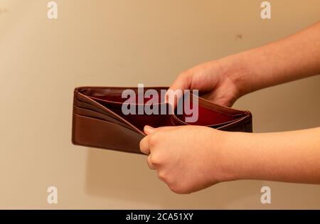 Crop view of Young man hands checking empty brown wallet. Due to slowdown in world economy, People are surviving for money. Stock Photo