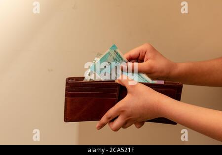 Crop view of young man hands while taking Indian currency notes from wallet. Stock Photo