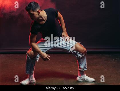 Young man professional dancer fond of dancing. dancing movements by caucasian man isolated in studio with red smoky background Stock Photo