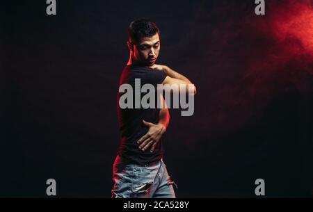 Young man professional dancer fond of dancing. dancing movements by caucasian man isolated in studio with red smoky background Stock Photo