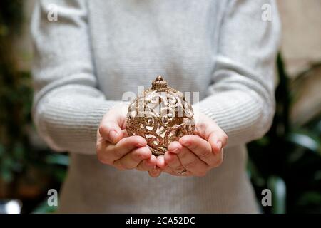 Close up of woman hands showing a gold christmas ball Stock Photo