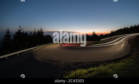light trails at evening from cars in a curve in germany. Stock Photo
