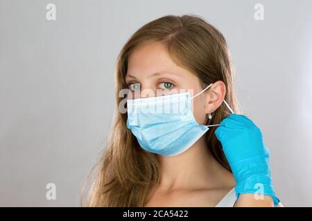 Young blonde woman putting on face mask in studio. Stock Photo