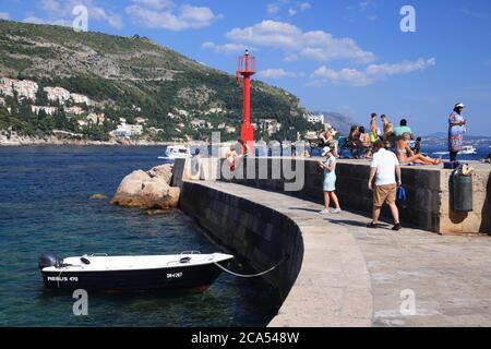 DUBROVNIK, CROATIA - JULY 26, 2019: Tourists visit a breakwater in Dubrovnik Harbor, a UNESCO World Heritage Site. Stock Photo
