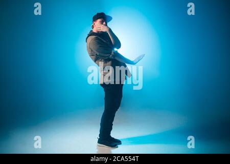 A dark silhouette of a singer on the stage, dancing alone during performance on dark blue neon background with smoke and lights. Stock Photo