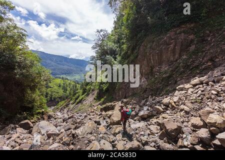 Indonesia, Papua, Baliem valley, near Wamena, Yali people territory, hiking trails towards Angguruk village, papuan porter walking down a rocky scree Stock Photo