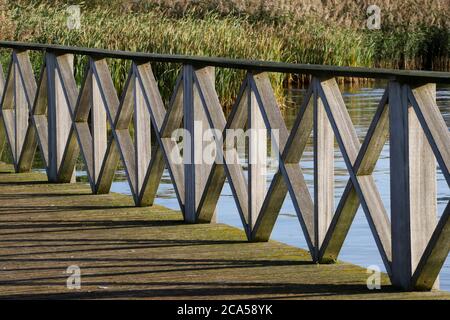 Patterns and shadows of a wooden boardwalk at Cardiff Bay nature reserve Stock Photo