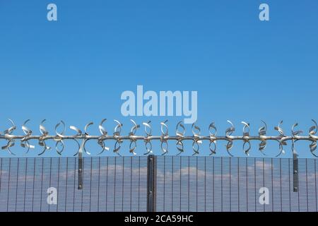 Restricted area.  Close up of barbed wire security fence against a blue sky Stock Photo