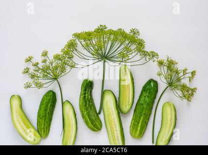 Halved cucumbers and fresh dill on a white surface. Stock Photo