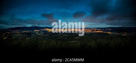 Dramatic moon sky with illuminated clouds in the mountains. Dark black silhouette of mountain ridge and Jested transmitter tower at the bottom, dark, Stock Photo