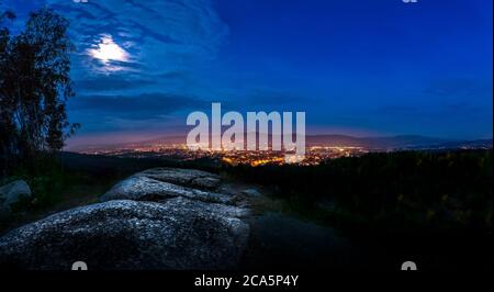 Dramatic Liberec moon sky with illuminated clouds in the mountains. Dark black silhouette of mountain ridge and Jested transmitter tower at the bottom Stock Photo