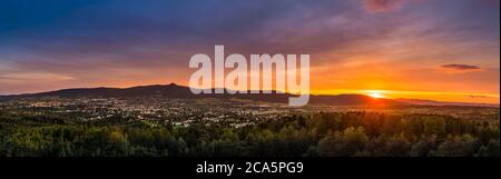 Dramatic Liberec sunset sky with illuminated clouds in the mountains. Dark black silhouette of mountain ridge and Jested transmitter tower at the bott Stock Photo