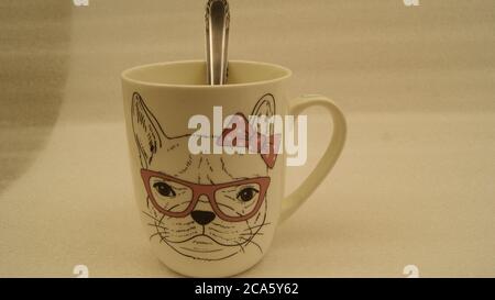 Ceramic mug with dog puppy design and spoon on white background, side view, Brazil, South America Stock Photo