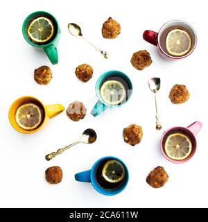 Many multi-colored mugs of lemon tea and homemade cookies on a white table. Stock Photo