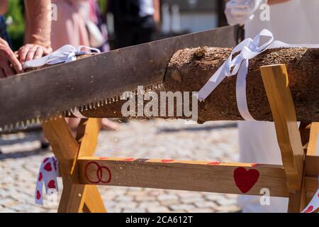 Bride and groom cutting wood log on sawhorse with copy space at wedding day Stock Photo