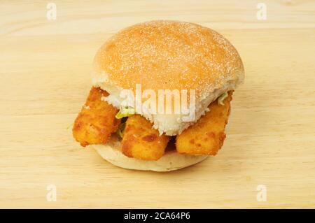 Fish fingers in a bread roll on a wooden chopping board Stock Photo