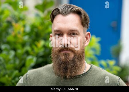 Outdoor portrait of a stylish handsome bearded Canadian man smiling confidently Stock Photo