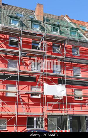 Old building is given a new red facade painting Stock Photo