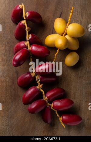fresh yellow and red dates on wooden background Stock Photo