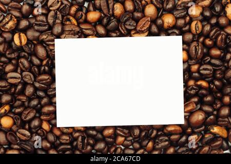 Coffee beans are scattered over the surface on a blank white background. a handful of brown coffee beans. Coffee background with copy space for Stock Photo