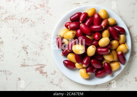 red and yellow fresh dates fruit in white plate Stock Photo