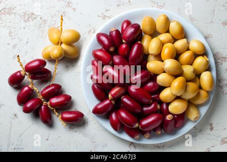 red and yellow fresh dates fruit in white plate Stock Photo