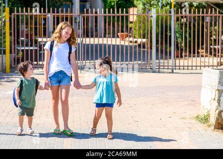 Happy school diverse children going to home outdoor at sunny day. Stock Photo