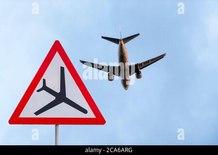 Airplane during take off and road airplane traffic sign, attention sign with plane, low flying aircraft. Stock Photo